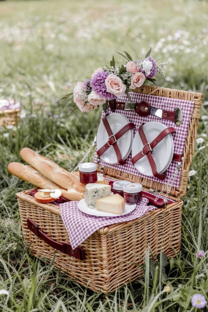 Cottagecore picnic basket with gingham napkins and artisan cheese
