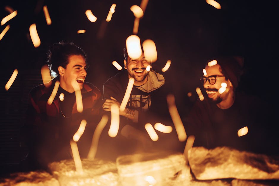 three friends laughing and enjoying a bonfire at night