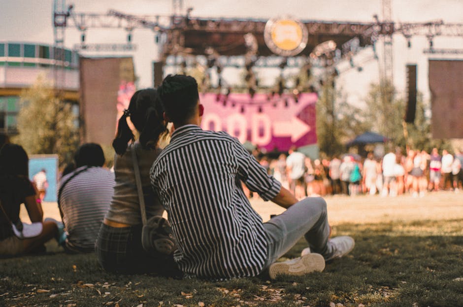 couple sitting on grass enjoying an outdoor music festival in summer