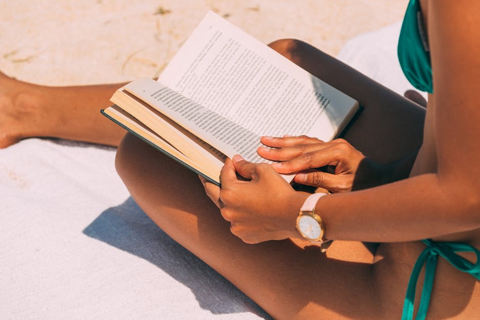woman reading a book on the beach in summer sunlight